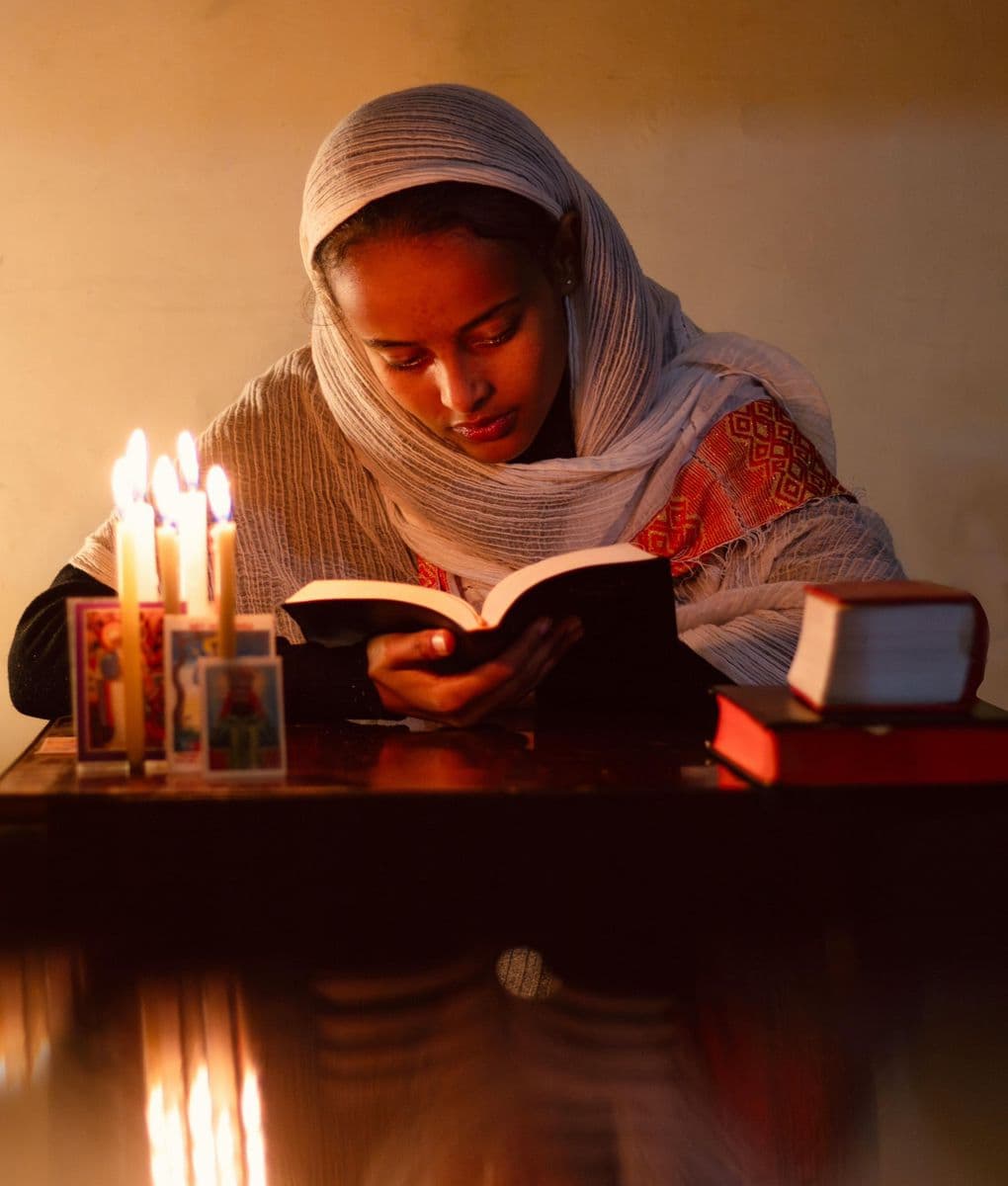 Woman reading a book by candlelight
